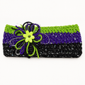 Handmade crocheted Halloween headband in purple, green, black, and silver with a loopy crochet flower and lime green button